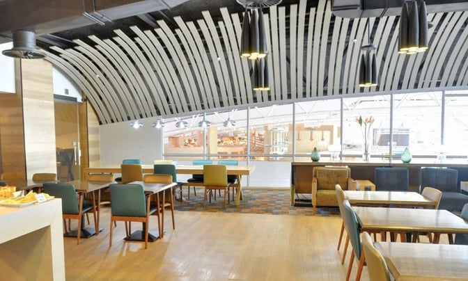 The Bidvest Premier Lounge at Cape Town International Airport features a seating area with tables and chairs, offering airport views.