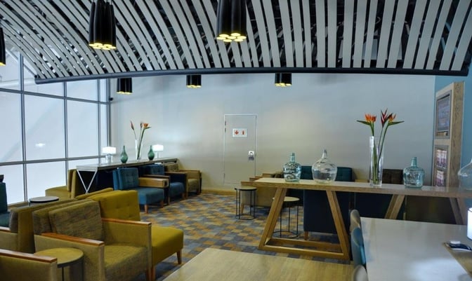 Seating area in Bidvest Premier Lounge at Cape Town International Airport features comfortable chairs and tables for relaxation and work.