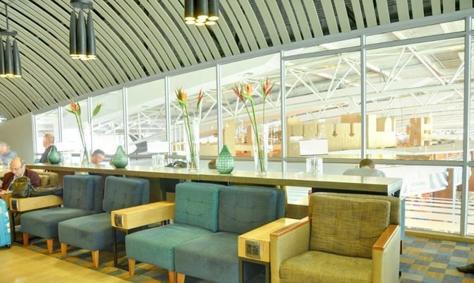 Seating area in Bidvest Premier Lounge at Cape Town International Airport features comfortable chairs and a counter with airport views.