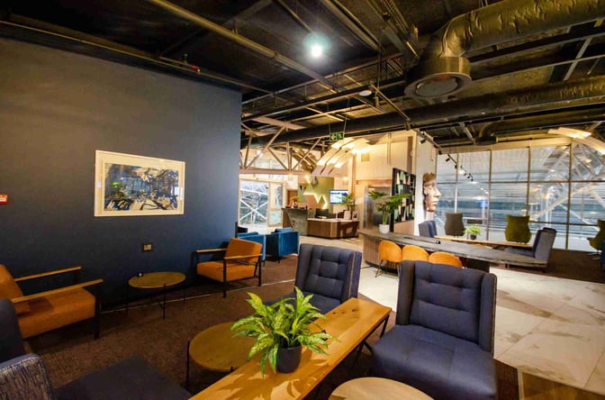 The Bidvest Premier Lounge at Cape Town International Airport features comfortable seating areas with tables and a reception desk nearby.