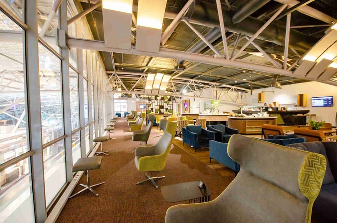The Bidvest Premier Lounge at Cape Town International Airport features comfortable seating with views of the terminal and a self-serve dining area.