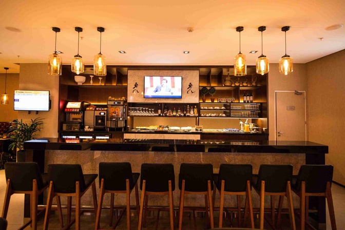 The bar at Aeropuertos VIP Club in Carrasco International Airport offers a selection of beverages and snacks with counter seating.