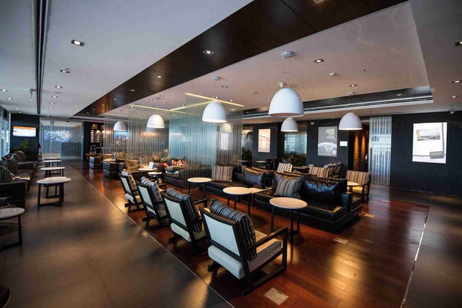The Aeropuertos VIP Club lounge at Carrasco International Airport features comfortable seating with tables, offering a relaxed waiting area for travelers.