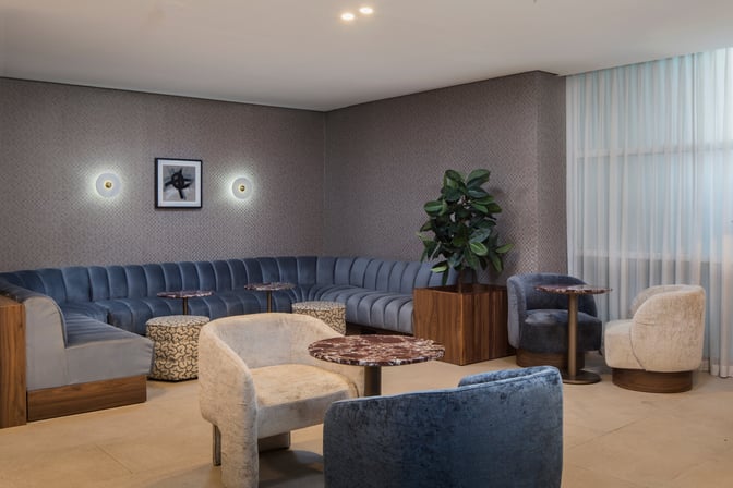The seating area in the Casablanca Aspire Lounge Terminal 2 features a curved sofa, individual chairs, and small tables for guest use.