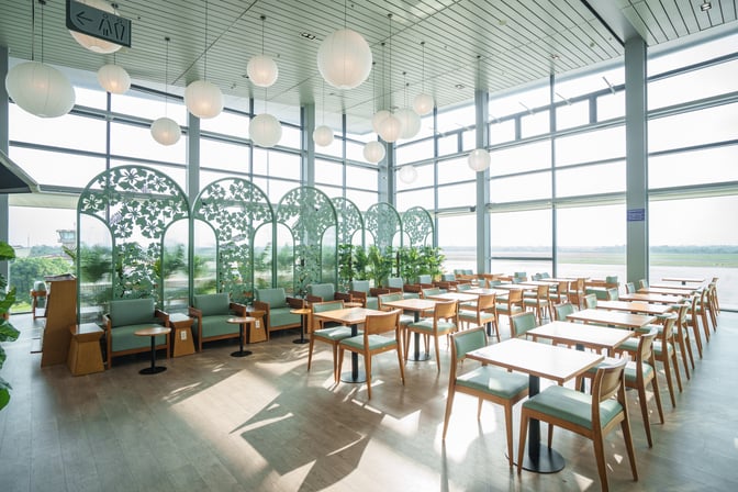 The seating area in SH Premium Lounge at Cat Bi International Airport offers tables and chairs with views of the runway.