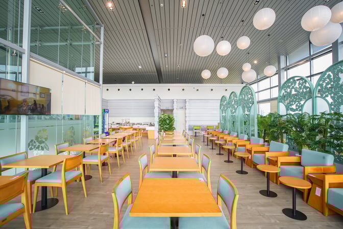 The SH Premium Lounge at Cat Bi International Airport features a spacious seating area with tables and chairs, alongside a self-serve food station.