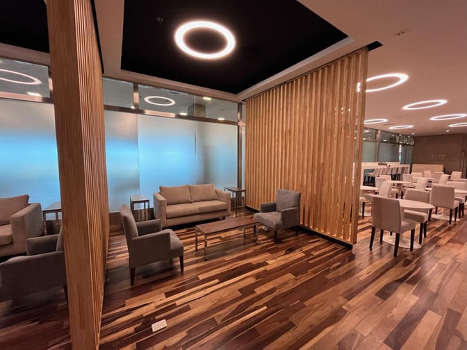 The Iguazu Lounge at Cataratas del Iguazú International Airport features comfortable seating areas with sofas and chairs, separated by wooden partitions.
