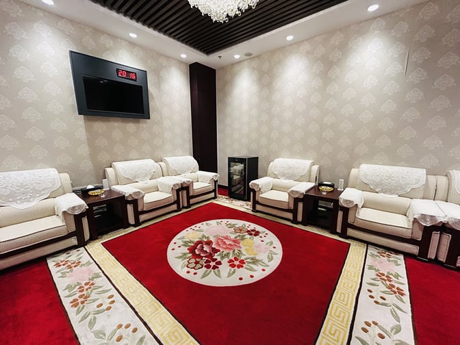 The VIP Lounge at Chengde Puning Airport features comfortable armchairs arranged around a floral-patterned carpet, with a wall-mounted clock and television.