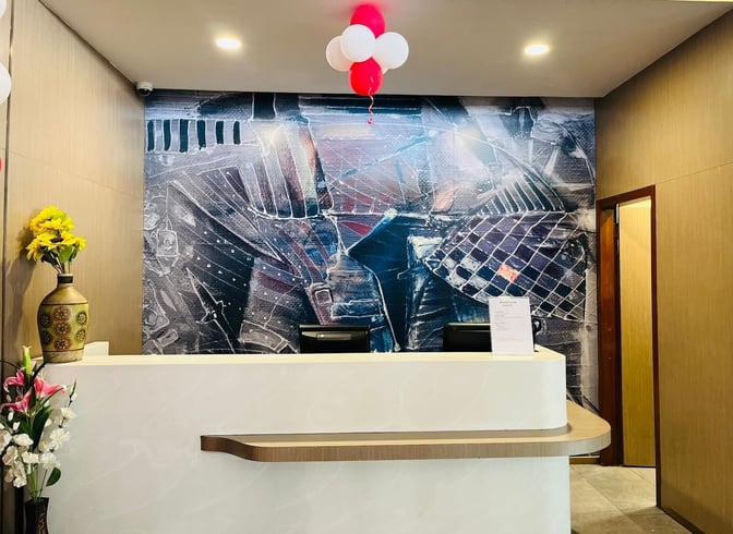 The reception area of Primus Lounge at Chandigarh Airport features a check-in counter with decorative wall art and floral arrangements.