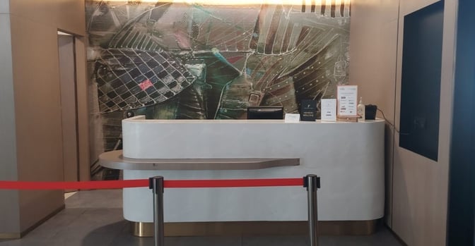 The reception desk at Primus Lounge, Chandigarh Airport, features a check-in counter with informational signage and a decorative backdrop.