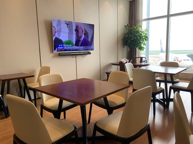 The seating area in the No. 2 First/Business Class VIP Lounge at Terminal 1 at Changsha Huanghua International Airport features tables, chairs, and a television.