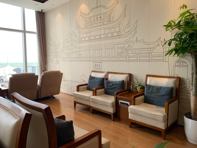 The seating area in the No. 2 First/Business Class VIP Lounge at Terminal 1 at Changsha Huanghua International Airport features comfortable chairs and a view of the runway.
