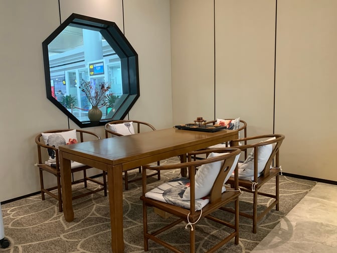 The No.6 Business Lounge at Changsha Airport features a seating area with a wooden table and chairs near a window.