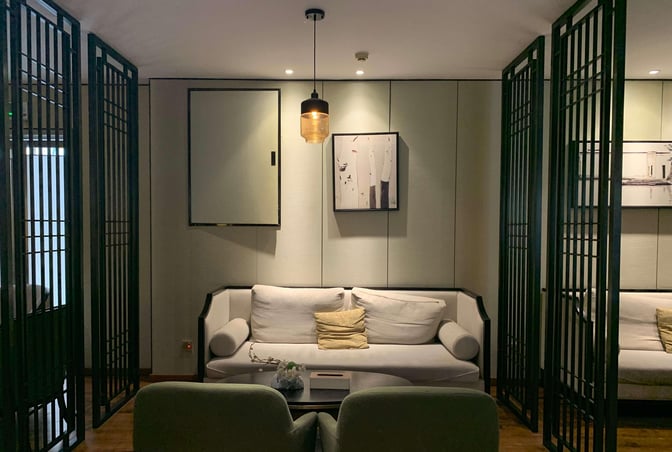 The seating area in Joyflight No.7 First Class Lounge features a sofa and chairs with decorative partitions for privacy.