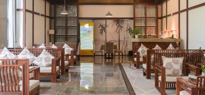 The Xiamen Airline VIP Center at Changsha Huanghua International Airport features wooden seating with cushions and a self-serve beverage area.