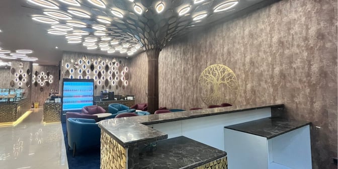 The Adani Lounge at Chaudhary Charan Singh International Airport Terminal 1 Domestic features a seating area with armchairs and a self-serve beverage station.