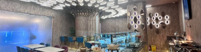 The Adani Lounge at Chaudhary Charan Singh International Airport Terminal 1 Domestic  features a dining area with tables, bar seating, and a buffet station.
