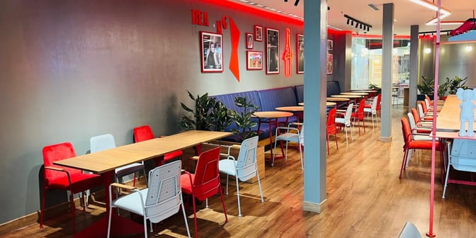 The seating area at Budweiser Bar in Chaudhary Charan Singh International Airport features tables with chairs and booth seating for travelers.