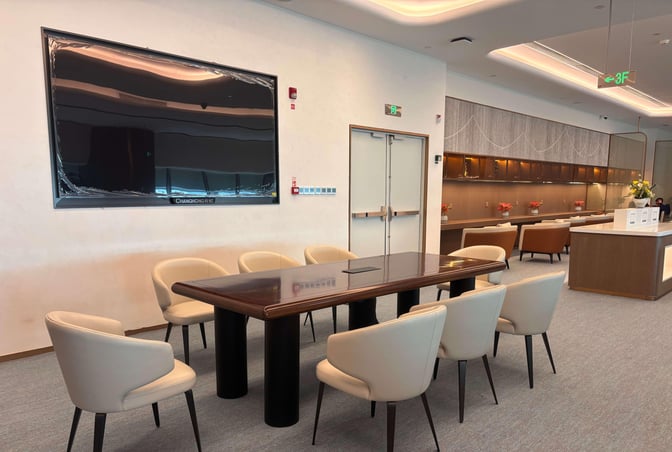 The seating area in Chengdu Shuangliu International Airport's airline lounge features a conference table with chairs and a wall-mounted screen.