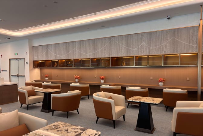 The seating area in Chengdu Shuangliu International Airport's airline lounge features comfortable chairs and tables with decorative shelving and power outlets.