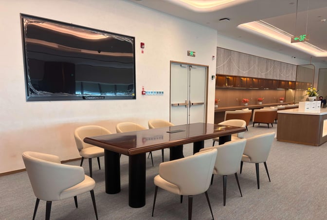 The seating area in Chengdu Shuangliu International Airport's airline lounge features a conference table with chairs and a wall-mounted screen.