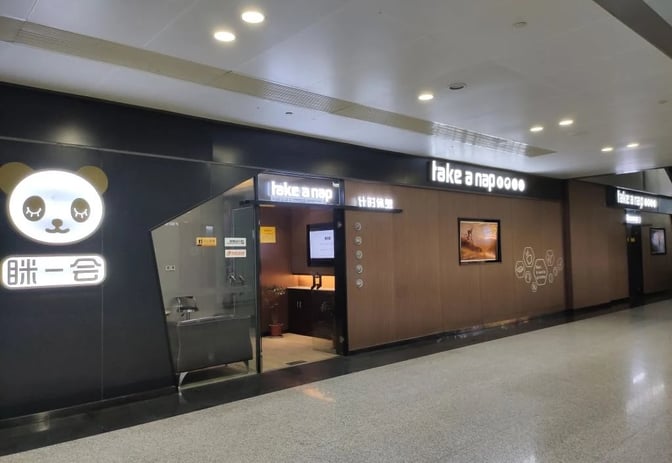 The entrance to the Take a Nap Business Lounge at Chengdu Shuangliu International Airport features a panda logo and digital signage.