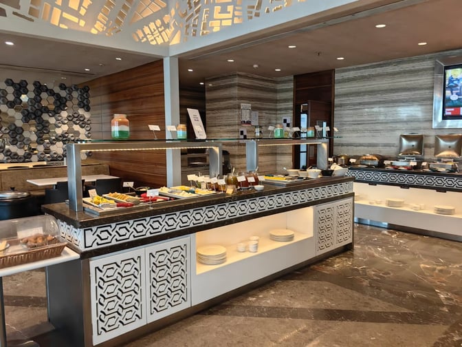 The Adani East Lounge at Chhatrapati Shivaji International Airport features a self-serve food area with a variety of dishes and condiments.