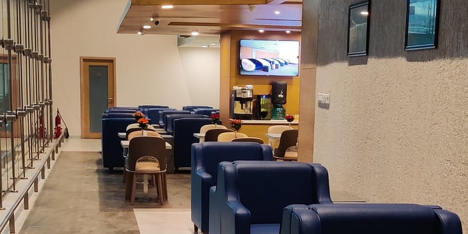 The Aviserv Lounge at Chhatrapati Shivaji International Airport features comfortable seating, a coffee machine, and a television for passenger relaxation.
