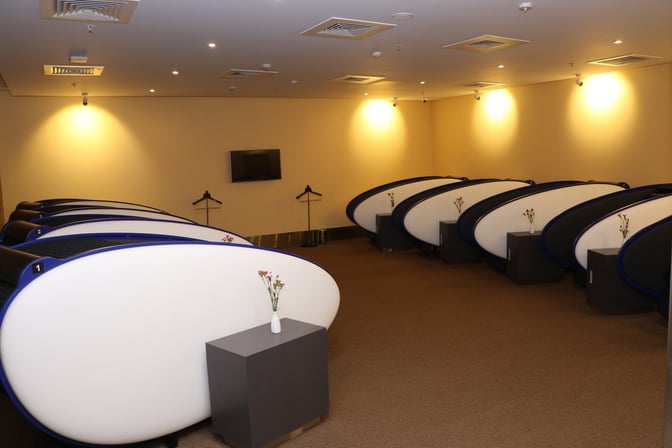 The Aviserv Lounge at Chhatrapati Shivaji International Airport features individual sleeping pods with small tables and hangers for passenger convenience.