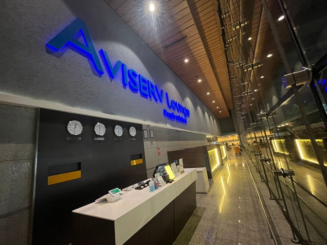 The entrance to Aviserv Lounge at Chhatrapati Shivaji International Airport features a reception desk and multiple world clocks.