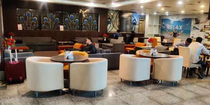 The Aviserv Lounge at Chhatrapati Shivaji International Airport features comfortable seating areas with tables, ideal for relaxation and work.