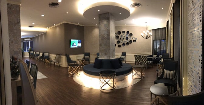 The seating area in Bangkok Airways Blue Ribbon Lounge at Chiang Mai International Airport features circular seating around a central column with nearby tables.
