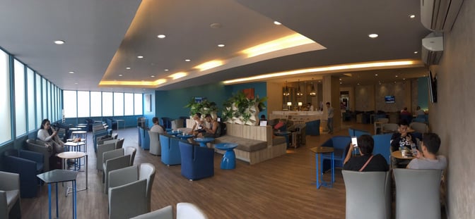 The Bangkok Airways Boutique Lounge at Chiang Mai International Airport features seating areas with tables and a self-serve snack station.