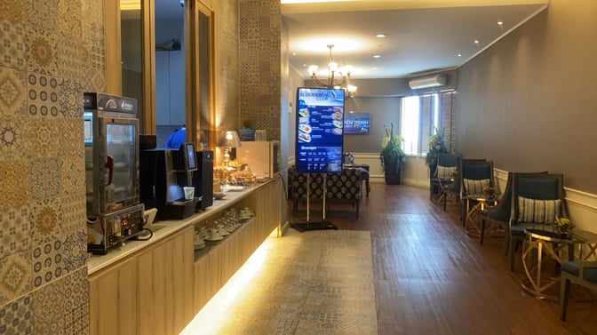 The Bangkok Airways Boutique Lounge at Chiang Mai International Airport features a self-serve beverage station and seating area with informational displays.