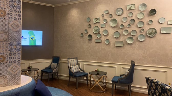 Seating area in Bangkok Airways Boutique Lounge at Chiang Mai Airport features comfortable chairs and decorative wall art for relaxation.