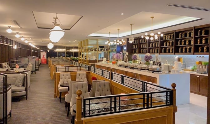 The Coral Executive Lounge at Chiang Mai International Airport features booth seating and a self-serve buffet with various food options.