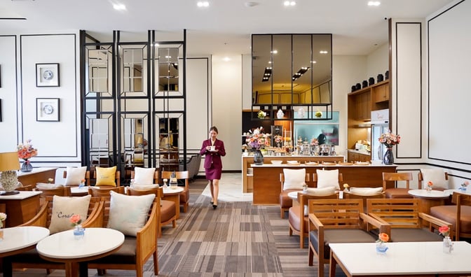 The Coral Executive Lounge at Chiang Mai International Airport features a seating area with tables and a self-serve food station.