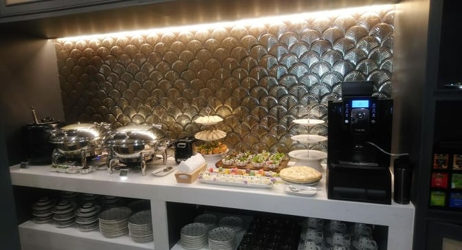 The Coral Executive Lounge at Mae Fah Luang International Airport features a self-serve food station with hot dishes, snacks, and a coffee machine.