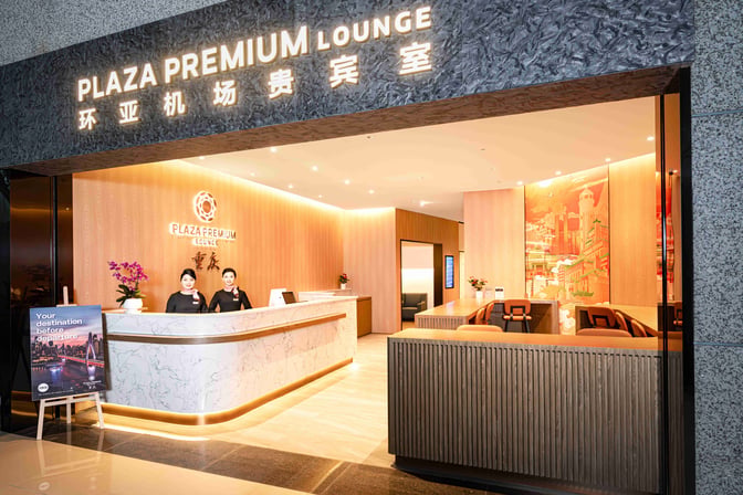 The entrance to the Plaza Premium Lounge at Chongqing Jiangbei International Airport features a reception desk staffed by attendants.