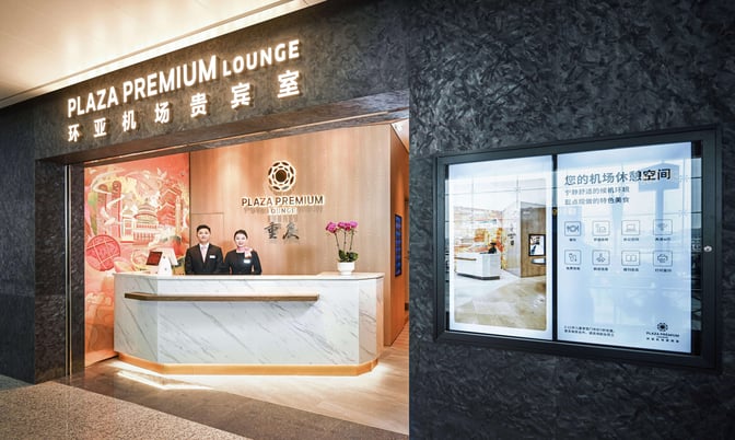 The entrance to the Plaza Premium Lounge at Chongqing Jiangbei International Airport features a reception desk with staff ready to assist.