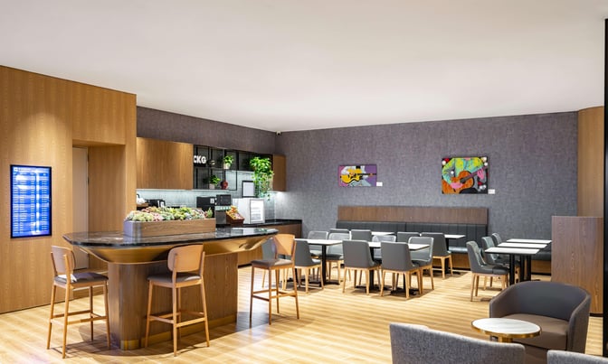 The Plaza Premium Lounge at Chongqing Jiangbei International Airport features a seating area with tables, chairs, and a central bar counter.