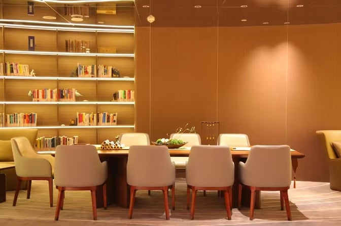 The lounge at Chongqing Jiangbei International Airport features a seating area with a large table and bookshelves for passenger use.