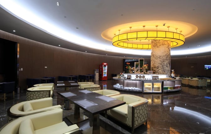 The International Lounge at Chongqing Jiangbei Airport features a central refreshment area with surrounding seating, offering snacks and beverages.