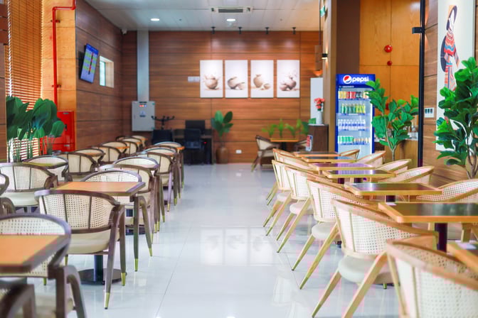 The SH Premium Lounge at Chu Lai International Airport features a seating area with tables and chairs, alongside a beverage cooler.