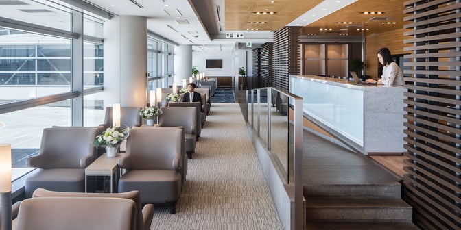 The Plaza Premium Lounge at Chubu Centrair International Airport features comfortable seating with runway views and a reception desk for guest assistance.