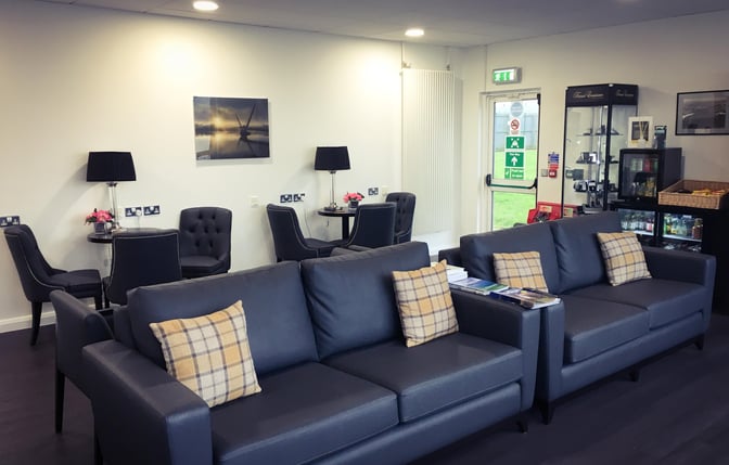 The Amelia Earhart Lounge at City of Derry Airport features comfortable seating areas with sofas, small tables, and a display cabinet.