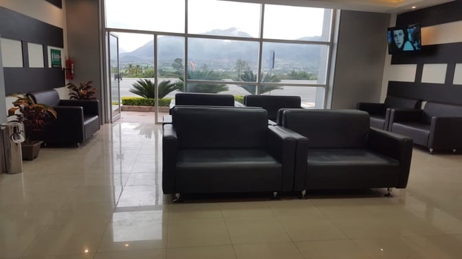 The seating area in Sala VIP Catamayo features comfortable chairs with views of the outdoors through large windows.