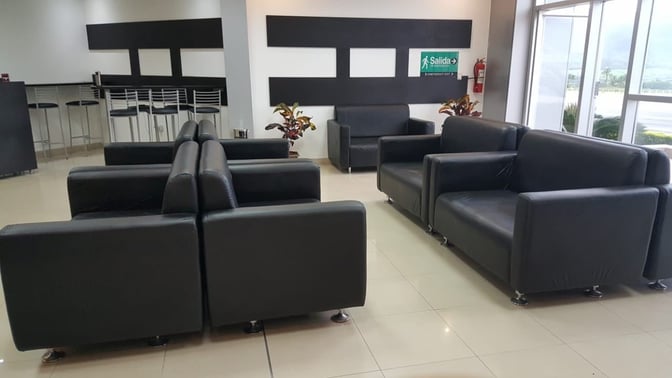 The seating area in Sala VIP Catamayo features multiple sofas and a bar counter with stools, offering airport views.