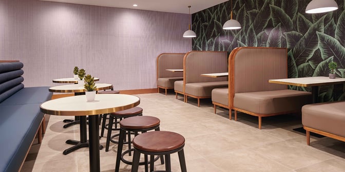 Booth seating at Plaza Premium Lounge, Clark International Airport, offers semi-private dining spaces with tables and stools for additional seating.