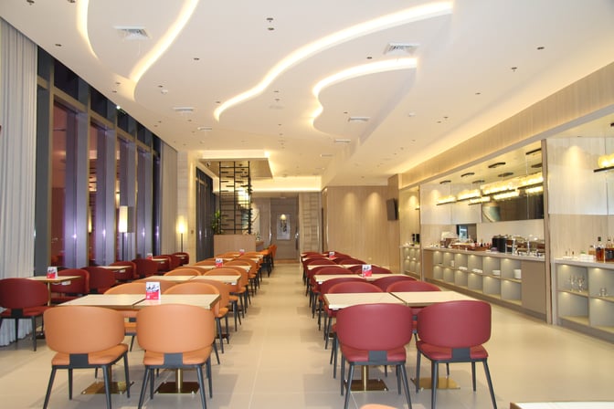 Seating area in Marhaba Lounge at Clark International Airport features rows of tables and chairs with a buffet station along one wall.